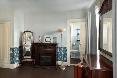 a living room with a fireplace and a mirror at Historic Rider's Hostelry in Painesville