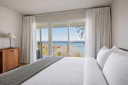 a bedroom with a large bed and a large window at The Herondale Hotel in Astoria, Oregon