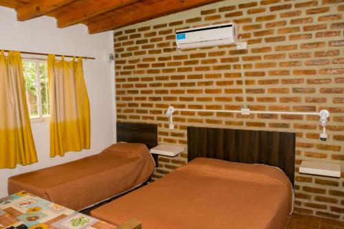 a bedroom with two beds and a brick wall at Cabañas de Campo in Villa Unión
