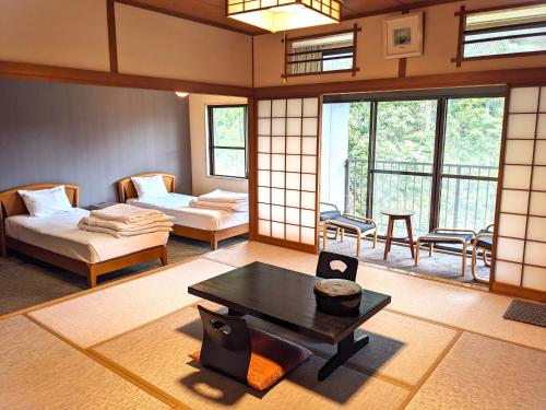 a room with two beds and a table in it at 霧島花紫 in Kirishima