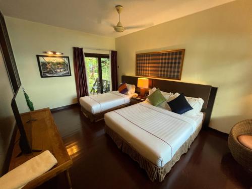 a hotel room with two beds and a table at Tunamaya Beach & Spa Resort Tioman Island in Tioman Island