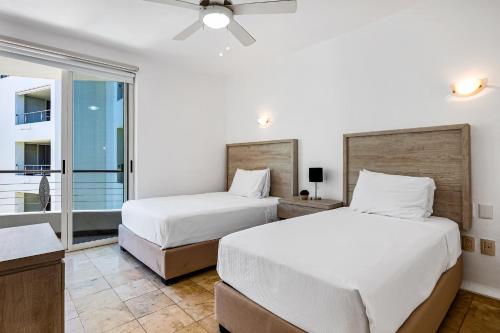 two beds in a room with a window at Stylish condo with covered balcony, pool & pool tables in Nuevo Vallarta