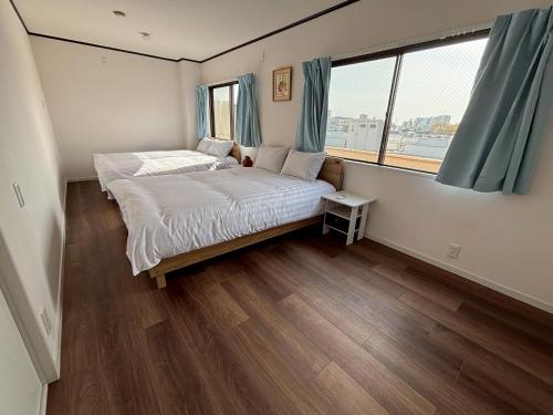 a bedroom with a bed and a large window at 京阪楽宿 in Kadoma
