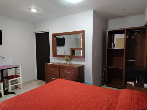 a bedroom with a bed and a dresser and a mirror at Hgen Rooms & Suites in Los Mochis