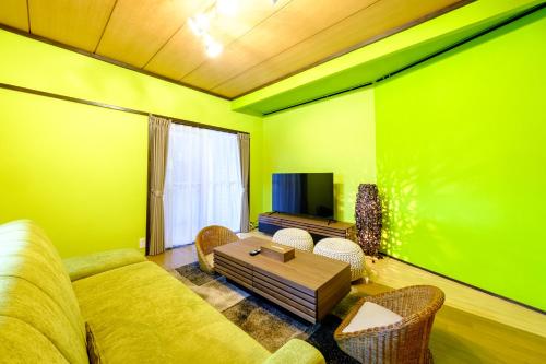 a green living room with a couch and a table at 六鶴亭-ビーチ徒歩8分,スーパー徒歩2分,駅徒歩12分 in Manazuru