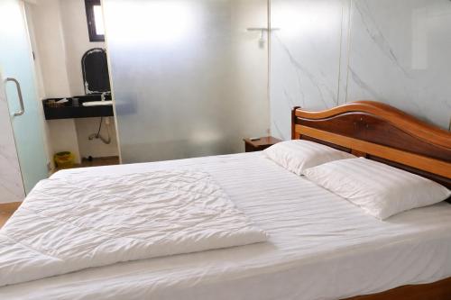 a white bed with a wooden headboard and white sheets at Tom Hotel Huế near Phu Bai Airport in Hue