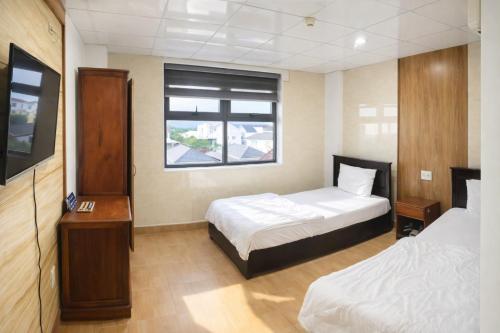 a hotel room with two beds and a window at Tom Hotel Huế near Phu Bai Airport in Hue
