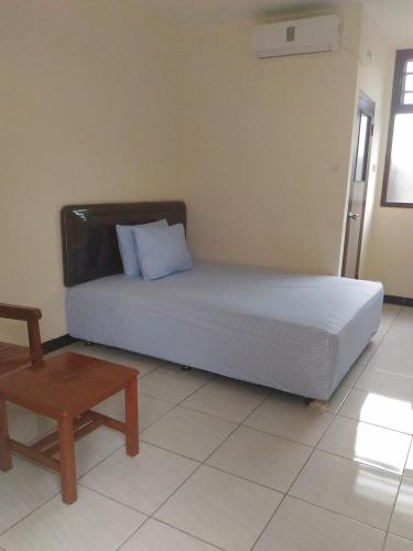 a bed in a room with a chair and a table at K15 Exclusive in Malang