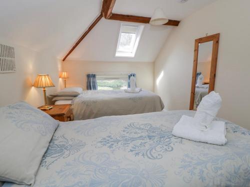 a bedroom with two beds and a mirror at Gardener's Cottage in Llandrindod Wells