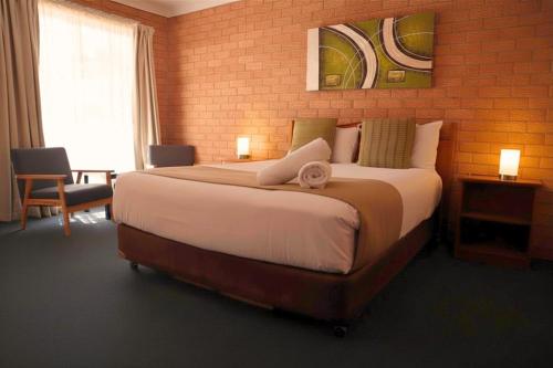 a large bed in a room with a brick wall at Golden Chain Aalana Motor Inn in Cowra