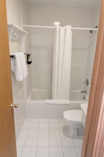 a white bathroom with a tub and a toilet at Motel 6 Lake George, NY Adirondacks in Lake George