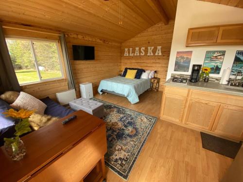 a living room with a bed and a kitchen at Rustic Moose Cabin at Moose Tracks Lodging in Kenai