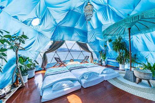 a man laying in a bed in a blue tent at ITOSHIMA SDGs Village Chikyu MIRAI -海の大パノラマ-全室オーシャンビューのドームテント in Itoshima