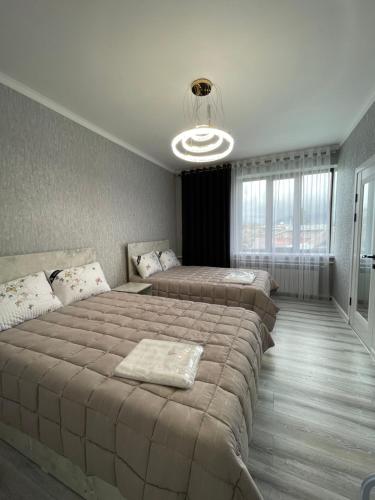 a bedroom with three beds and a chandelier at Karakol Aksuu guest house in Teploklyuchinskoye