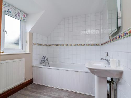 a white bathroom with a tub and a sink at Manor Wood in Coddington