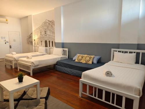 a room with two beds and a table in it at Chino Town at Yaowarat Phuket - SHA Plus in Phuket