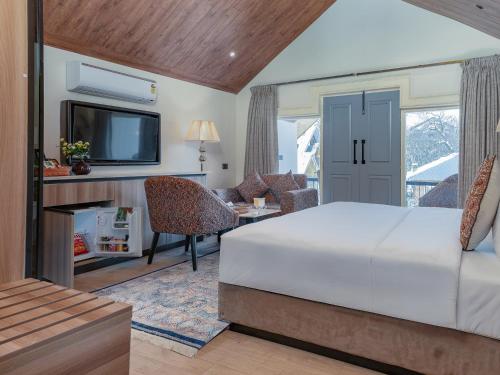 a bedroom with a bed and a living room with a tv at Faiz Resort Pahalgam in Pahalgām