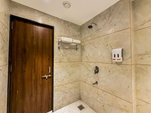 a bathroom with a shower with a wooden door at ZiP By Spree Hotels Pandharpur in Pandharpur