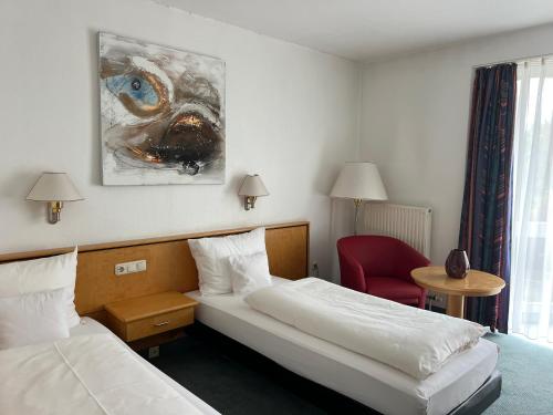 a hotel room with two beds and a red chair at Matchpoint Hotel in Altdorf bei Nuernberg