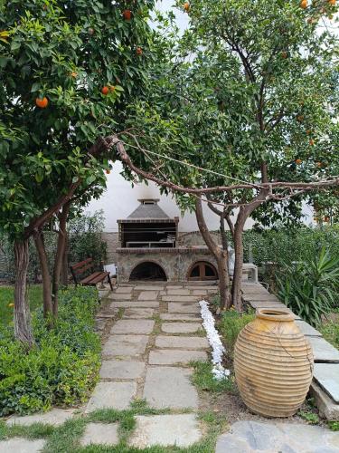 a garden with a stone fireplace and a vase next to trees at Betty's Garden House in Nea Anchialos