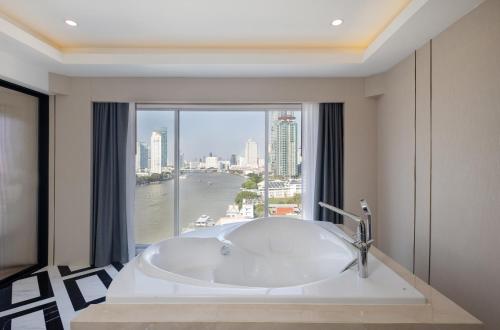 a bath tub in a bathroom with a large window at Ramada Plaza by Wyndham Bangkok Menam Riverside in Bangkok