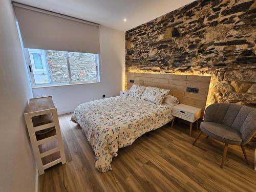 a bedroom with a bed and a stone wall at Apartamento Plaza de Armas 2 in Ferrol