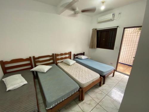 two twin beds in a room with a window at Dina Suítes Flat's Caiçara in São Sebastião