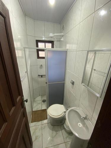 a white bathroom with a toilet and a sink at Dina Suítes Flat's Caiçara in São Sebastião