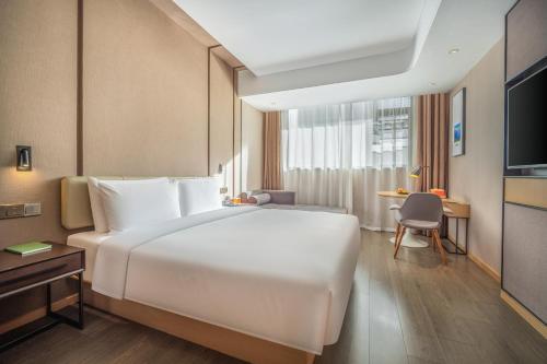 a bedroom with a large white bed and a desk at Atour Hotel Kunming Jiantou Building Jingkai District in Kunming