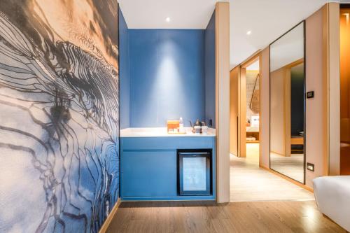 a living room with a blue wall with a fireplace at Atour Hotel Kunming Jiantou Building Jingkai District in Kunming