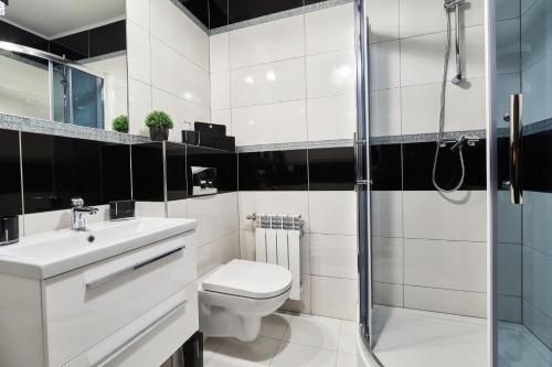 a white bathroom with a toilet and a shower at Apartament Perła Pienin in Dębno