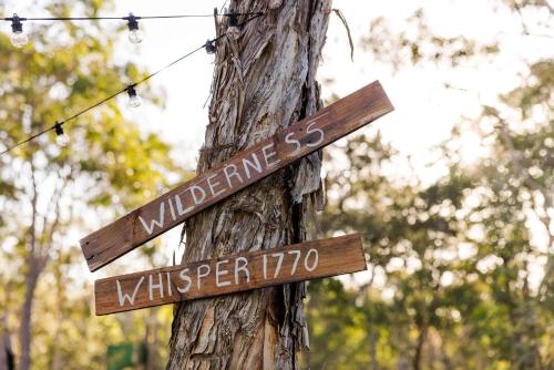 a pole with two wooden signs on a tree at Wilderness Whisper 1770 By Tiny Away in Agnes Water
