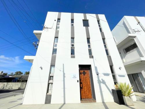 a white building with a wooden door at White Cube Yagaji 沖縄 - Kouri Churaumi - 1min Beach-Max 10ppl-2 Parking in Nago