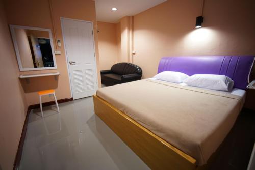 a bedroom with a bed with a purple headboard and a chair at Urban Hostel Bangkok in Bangkok
