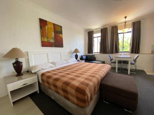 a hotel room with a large bed and a desk at Stonestown Suites in Balulang