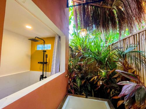 a bathroom with a shower with plants on the wall at Cosy Villa & Apartments - Siargao in General Luna