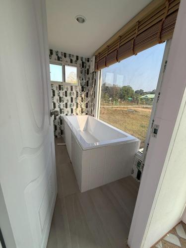 a white bath tub in a bathroom with a window at Peace poolvilla sattahip พีซ พลูวิลล่า สัตหีบ in Ban Tao Than