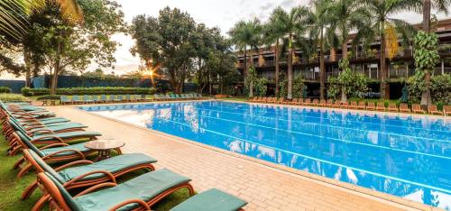 a resort pool with lounge chairs and palm trees at Afro-American Motel in Kampala