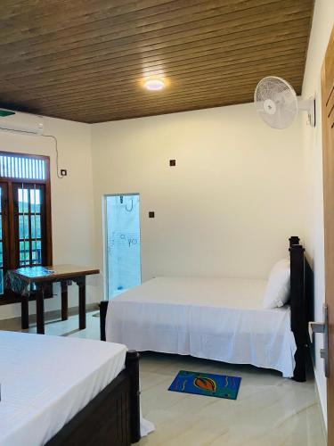 a bedroom with two beds and a table and a desk at Sawmya Guest House in Randeniya