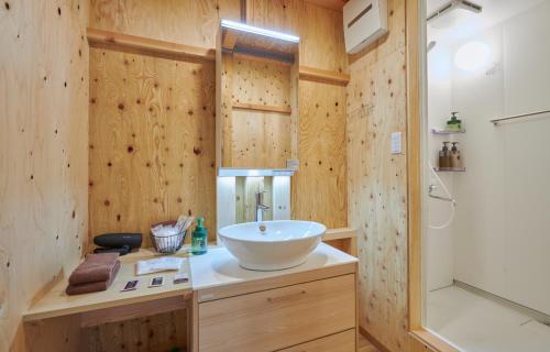 a bathroom with a white sink and a shower at 森のRetreat -foresta di luce- in Hatsukaichi