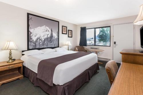 a hotel room with a large bed and a desk at Super 8 by Wyndham Kelowna BC in Kelowna