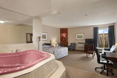 a bathroom with a pink tub in a hotel room at Travelodge by Wyndham Cambridge - Waterloo in Cambridge