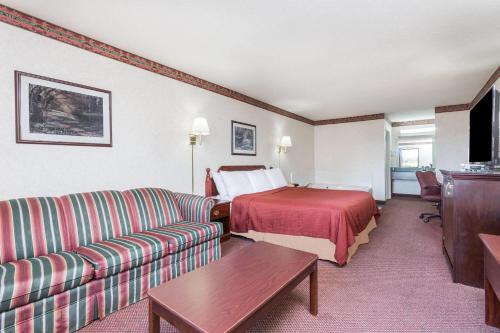 a hotel room with a bed and a couch at Days Inn by Wyndham Royston in Royston