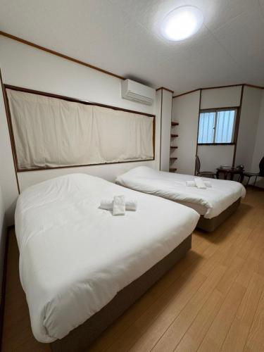 two beds in a hotel room with white sheets at GOOSESTAY Koza in Okinawa City