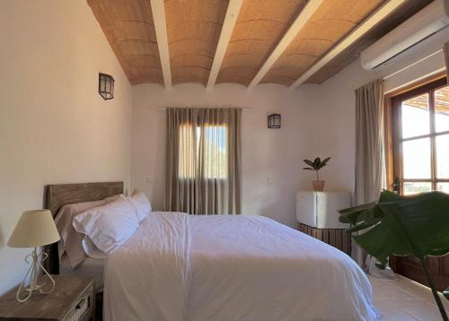 a bedroom with a white bed and a large window at Balearic Sunset Apartment in Santa Gertrudis de Fruitera