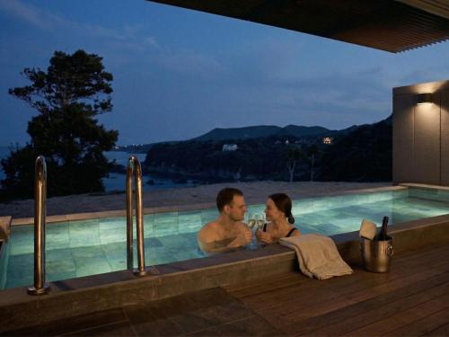 a man and a woman sitting in a swimming pool at Oyado The Earth in Toba