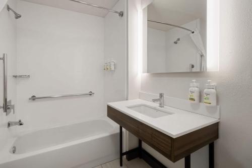 a white bathroom with a sink and a bath tub at La Quinta by Wyndham Savannah Airport - Pooler in Savannah