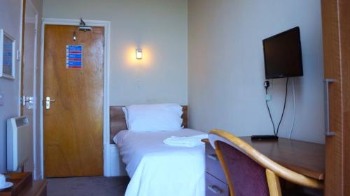 a hotel room with a bed and a desk and a television at Oban Hotel in Eastbourne