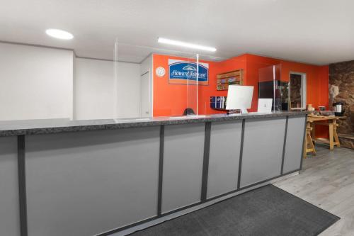 a kitchen with white cabinets and an orange wall at Howard Johnson by Wyndham Edson in Edson