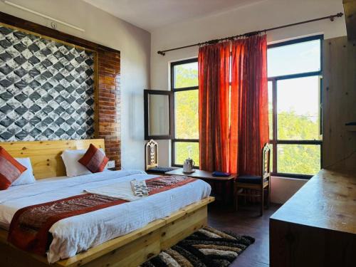 a bedroom with a large bed and two windows at Hotel Sumit in Kausani